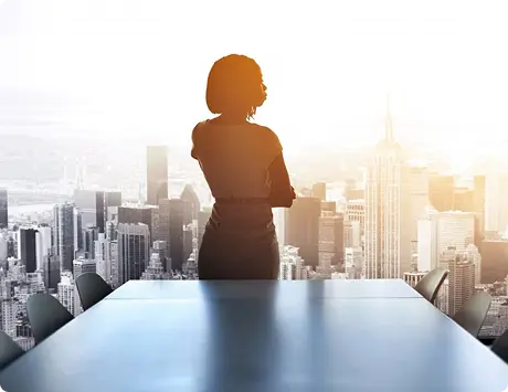 Silhouette of a woman gazing out over a city skyline, with skyscrapers and the Empire State Building visible. Bright, hopeful ambiance.